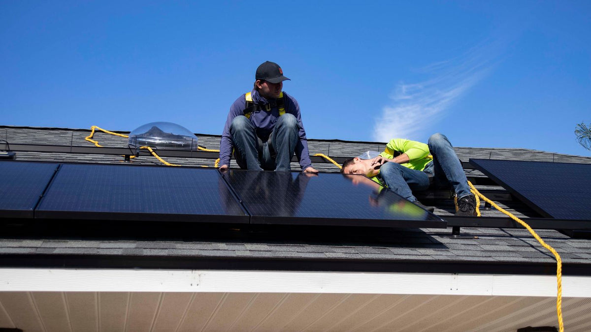 Installateurs posant des panneaux photovoltaïques sur le toit d’une maison
